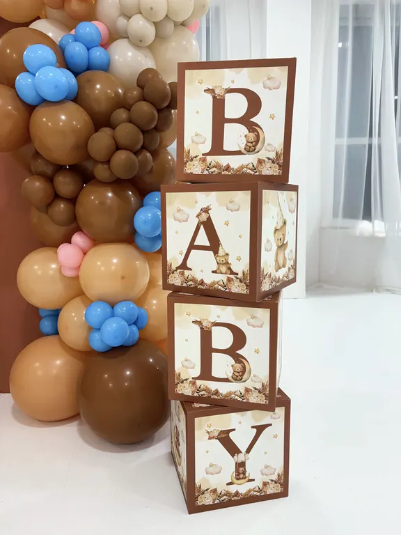 Baby shower balloon garland in brown, cream and blue beside stacked blocks spelling Baby