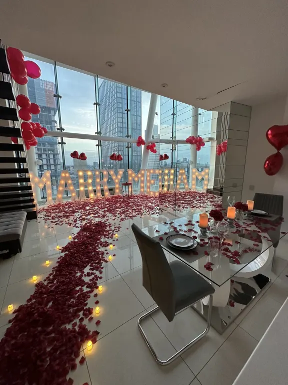 Light-up Marry Me letters and a path of rose petals above the Manchester skyline