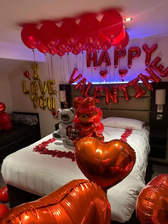 Hotel room filled with red balloons and foil hearts for Valentine's Day