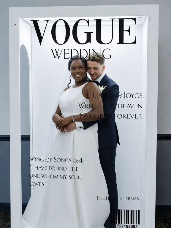 Bride and groom posing inside a life-size Vogue Wedding magazine cover frame